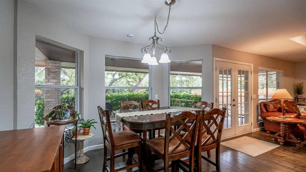 511 Casas Del Norte Court, Granbury, TX 76049 Breakfast area featuring bay windows, wood-finish flooring, a pendant light fixture, and glass-paneled french doors to access covered rear porch
