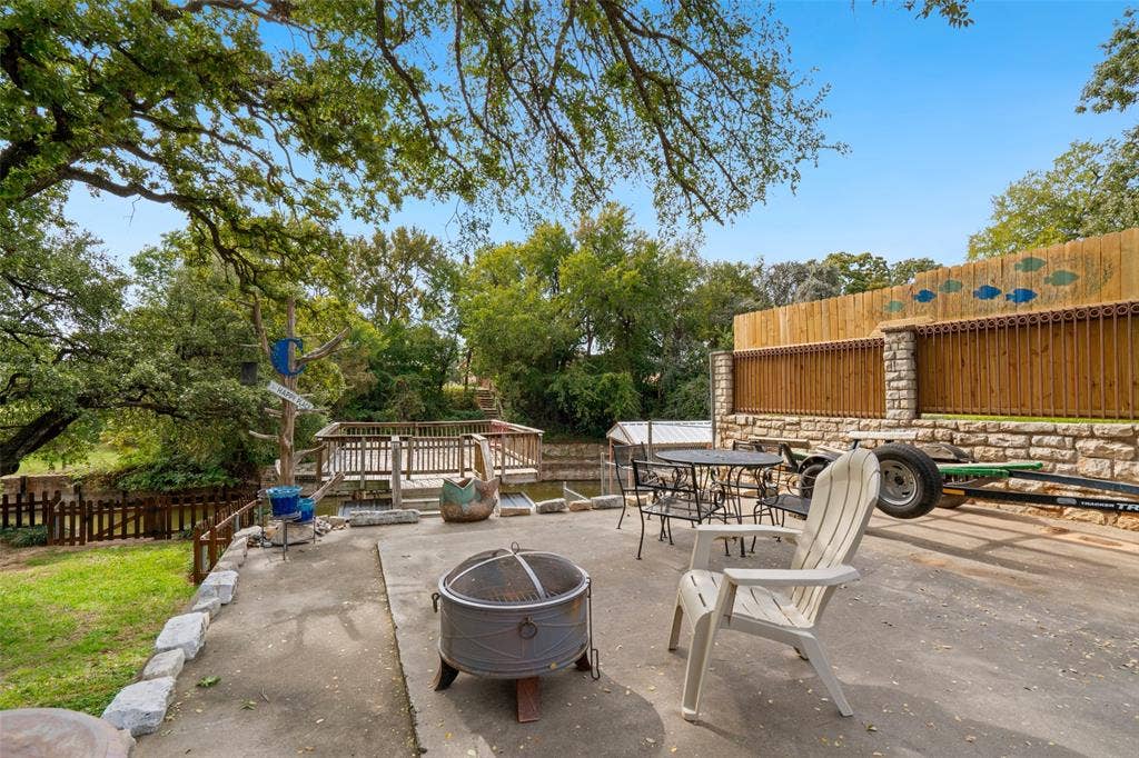 511 Casas Del Norte Court, Granbury, TX 76049 Concrete patio featuring a stacked stone and wooden perimeter fencing, and a wooden deck overlooking lake Granbury accented by mature shade trees
