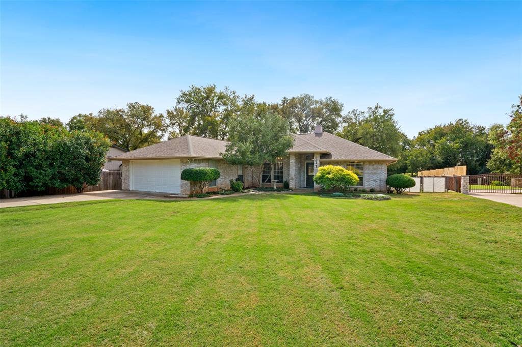 511 Casas Del Norte Court, Granbury, TX 76049 Single-story brick exterior with an attached two-car garage, and an expansive front lawn with mature landscaping
