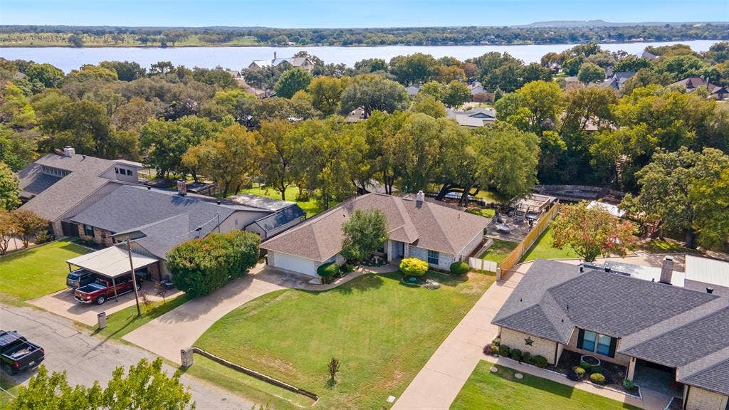 511 Casas Del Norte Court, Granbury, TX 76049 Aerial perspective featuring expansive lawns, mature trees, and waterfront scenery