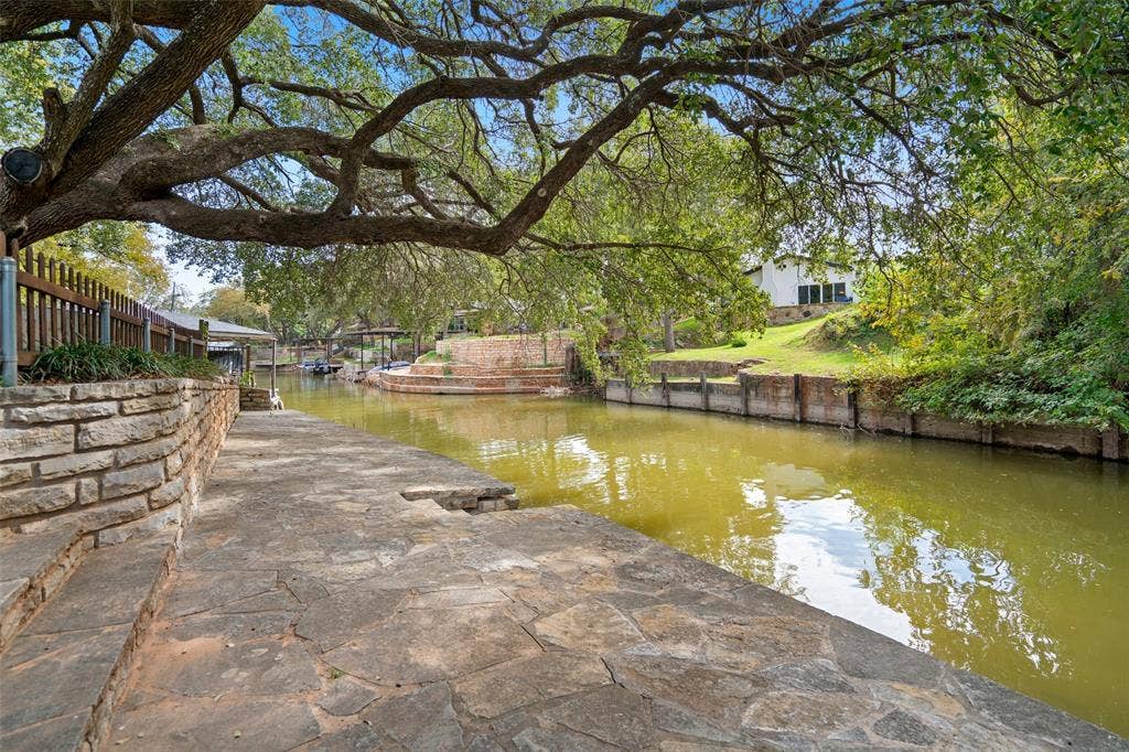 511 Casas Del Norte Court, Granbury, TX 76049 Waterfront view property featuring a flagstone and stacked stone retaining walls, and mature canopy trees