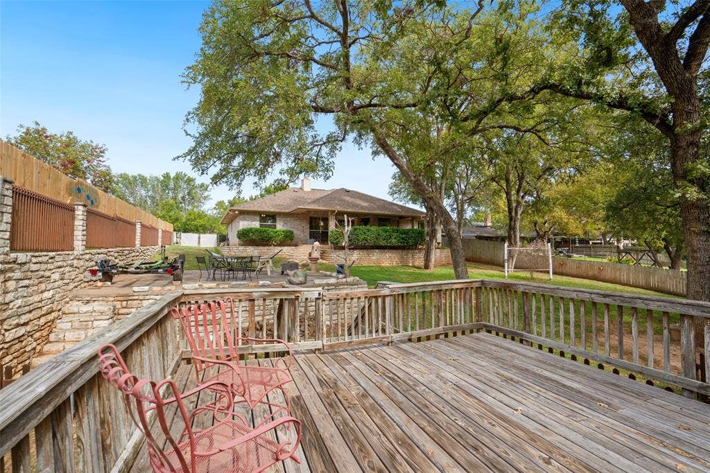 511 Casas Del Norte Court, Granbury, TX 76049 Multi-level wood decking featuring a railed perimeter, stone retaining wall, and mature shade trees
