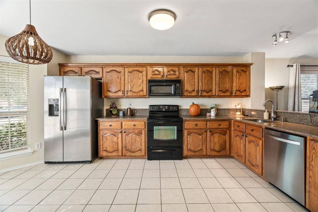 2750 Chalmers Court, Rockwall, TX 75032 The kitchen boasts a pantry, SS refrigerator, SS dishwasher, an electric range and a microwave.
