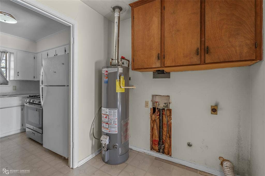 Utility room featuring wall-mounted wood cabinetry, a vertical water heater, and washer and dryer hookups with accessible plumbing access