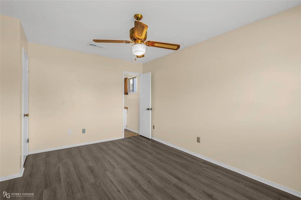 Neutral interior space featuring wood-finish flooring, a ceiling fan with integrated lighting, and white interior doors
