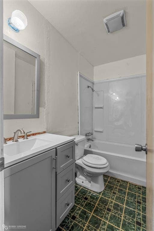Bathroom featuring a gray vanity with a white countertop, integrated sink, wall-mounted mirror, white tub-and-shower combination, and tiled flooring