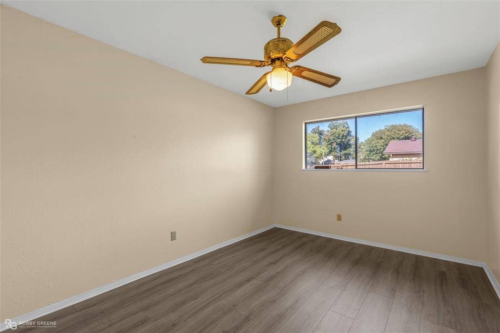 Room featuring wood-finish flooring, a horizontal sliding window, and a ceiling-mounted fan with integrated light fixture