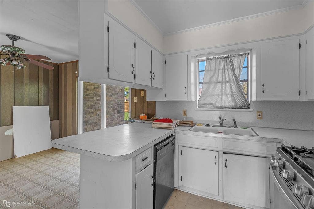 Kitchen featuring white cabinetry, a dual-basin sink, integrated dishwasher, gas range, and extended countertop peninsula
