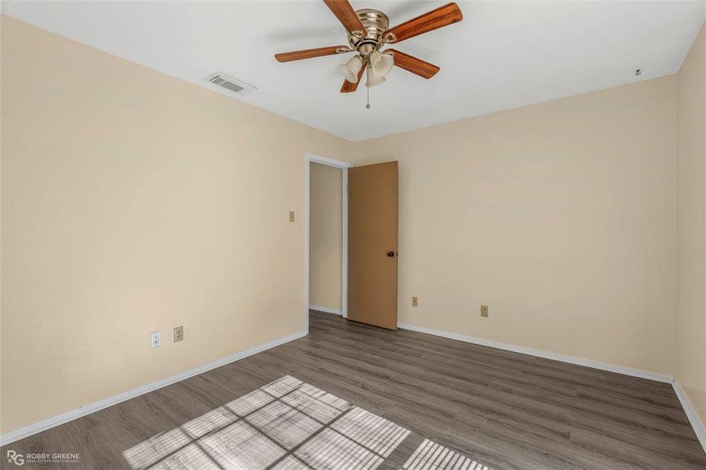 Interior space featuring wood-finish flooring, neutral wall paint, and a ceiling fan with integrated lighting