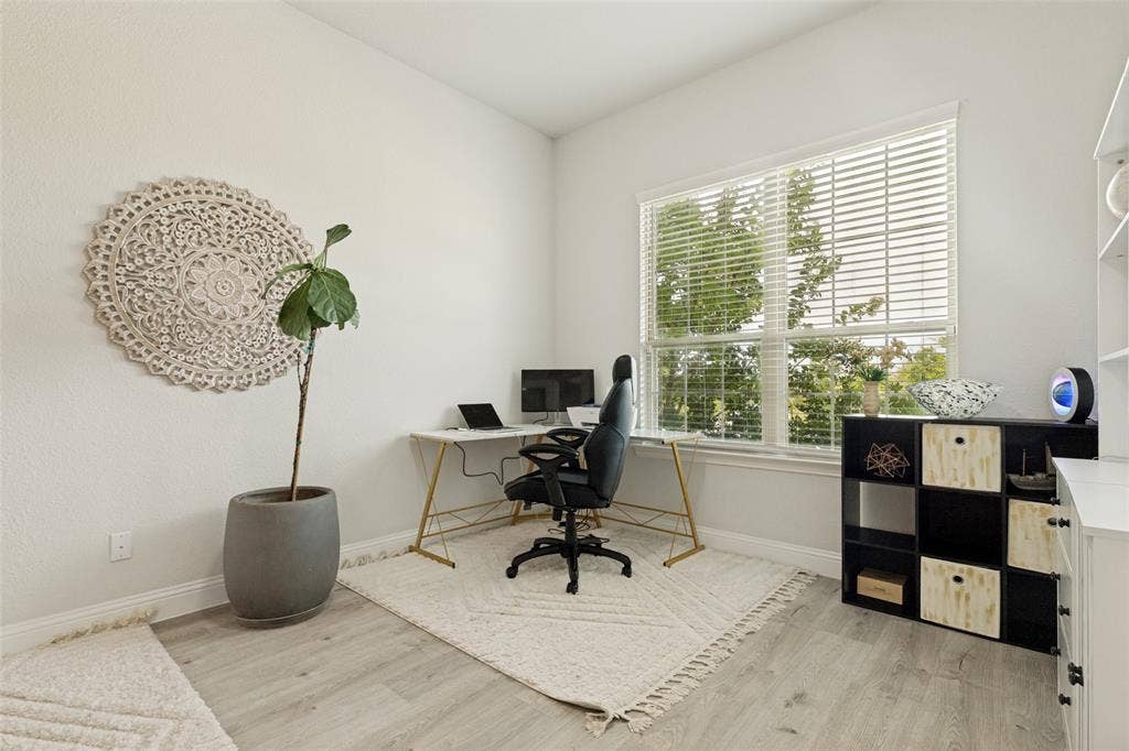 16931 Maple Bend Drive, Frisco, TX 75035 Neutral-toned room featuring wood-finish flooring, a large multi-pane window with adjustable horizontal blinds, and built-in shelving