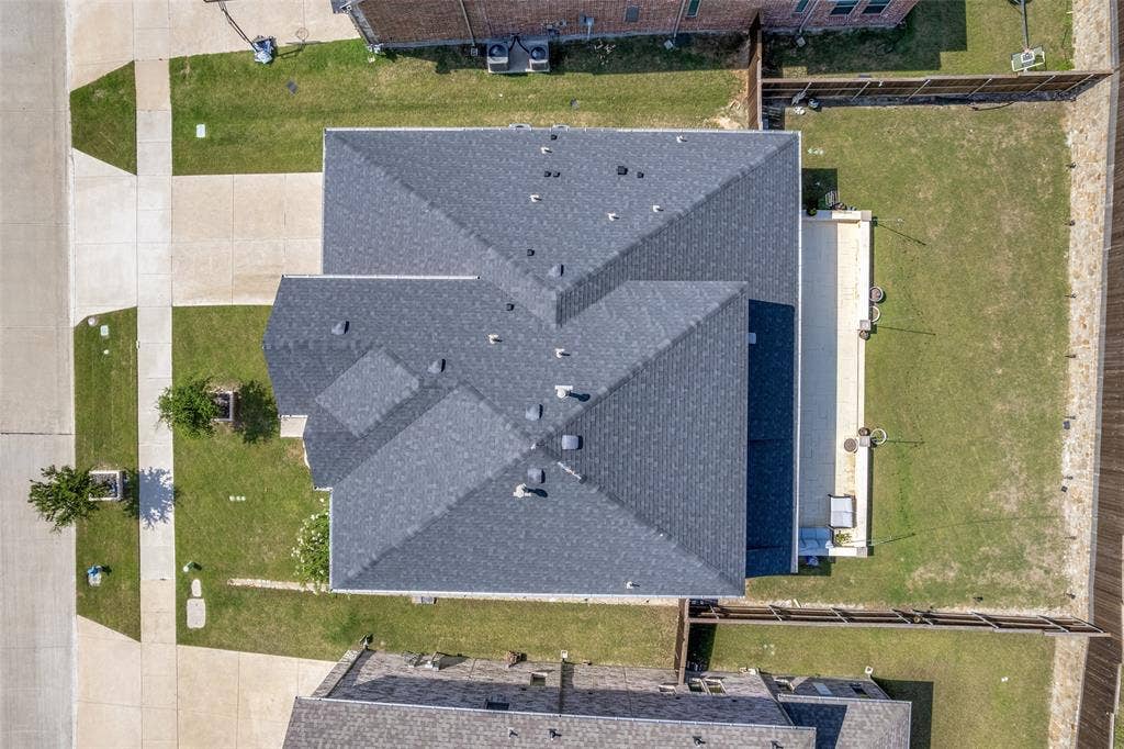 16931 Maple Bend Drive, Frisco, TX 75035 Aerial perspective showcasing a property with a multi-gabled shingled roof, a paved patio, and a fenced yard
