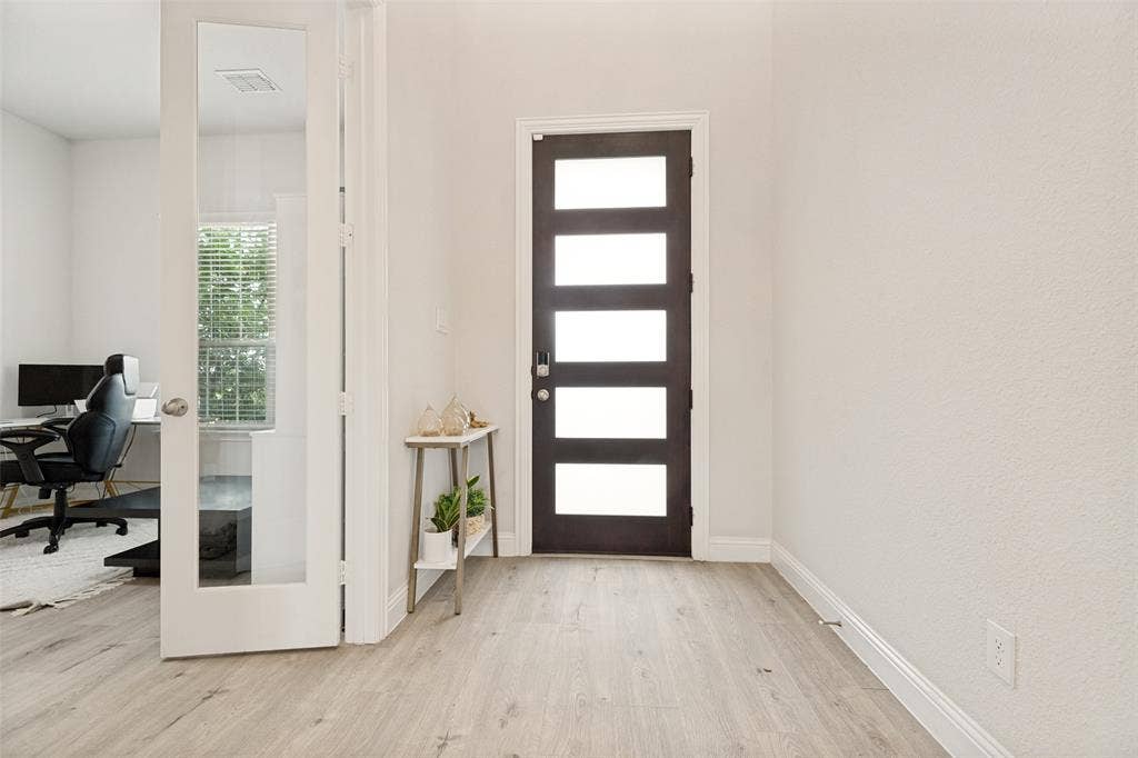16931 Maple Bend Drive, Frisco, TX 75035 Entryway featuring wood-finish flooring, a contemporary dark-toned front door with five horizontal glass panels, and a swinging door with a full-length glass pane