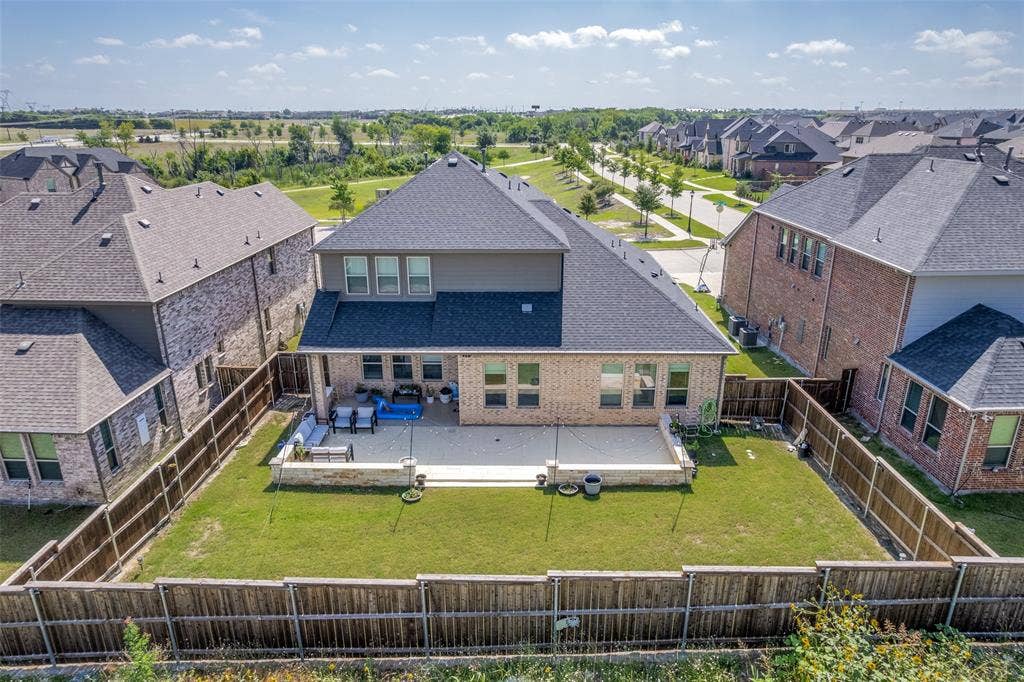 16931 Maple Bend Drive, Frisco, TX 75035 Backyard featuring a paved stone patio, retaining wall, manicured lawn, and wood privacy fencing