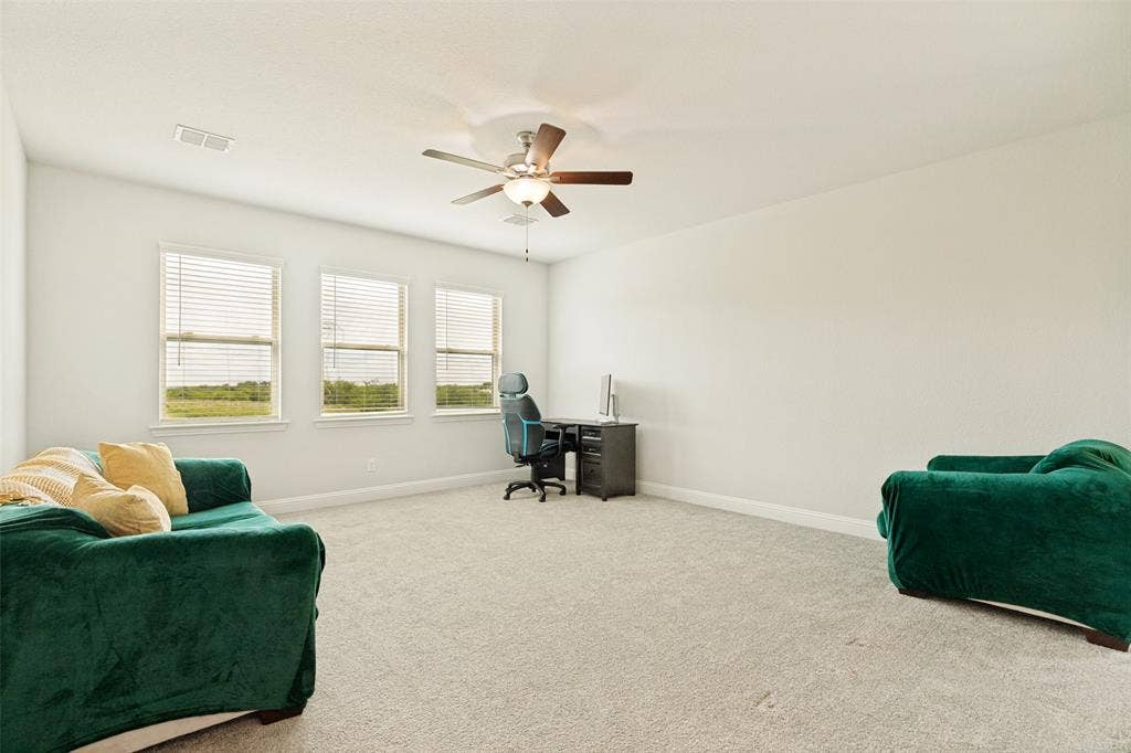 16931 Maple Bend Drive, Frisco, TX 75035 Neutral-toned carpeting, triple-window configuration with horizontal blinds, and a central ceiling fan with integrated lighting