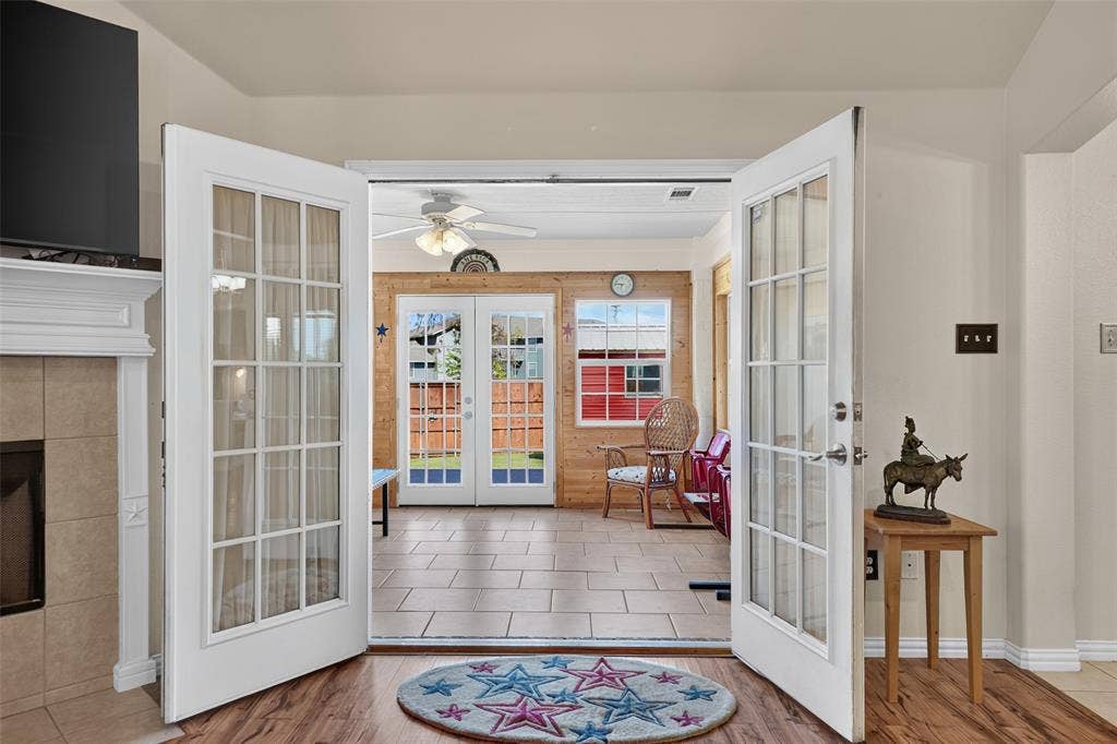 8700 Broken Bow Drive, Greenville, TX 75402 Double French doors with glass panes lead to this beautifully remodeled sunroom with wood-paneled walls, ceiling fan and French doors to the backyard.