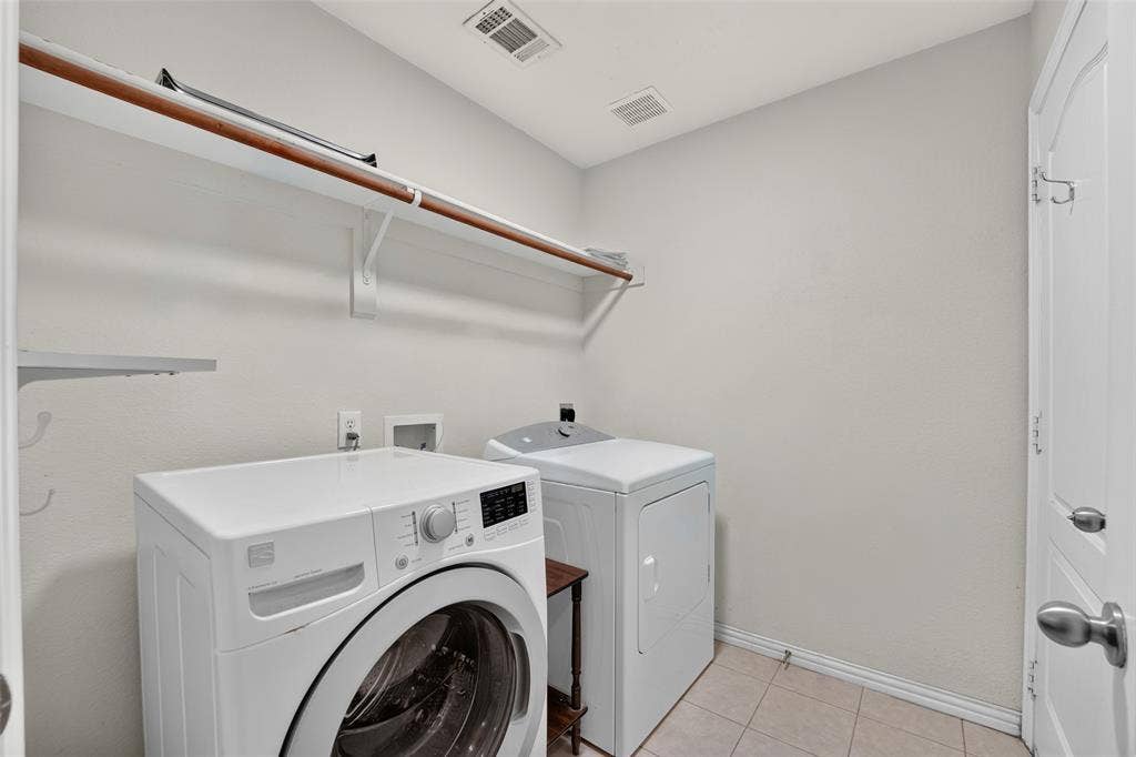 8700 Broken Bow Drive, Greenville, TX 75402 Laundry room featuring tile flooring, neutral wall paint, and overhead shelf storage. WASHER & DRYER CONVEY!