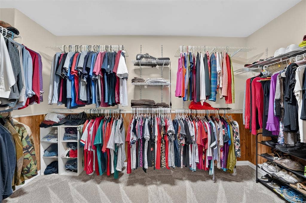 8700 Broken Bow Drive, Greenville, TX 75402 Spacious walk-in closet with cedar paneled lower walls featuring multi-level wire shelving, double hanging rods, ample storage space, and neutral carpeting.