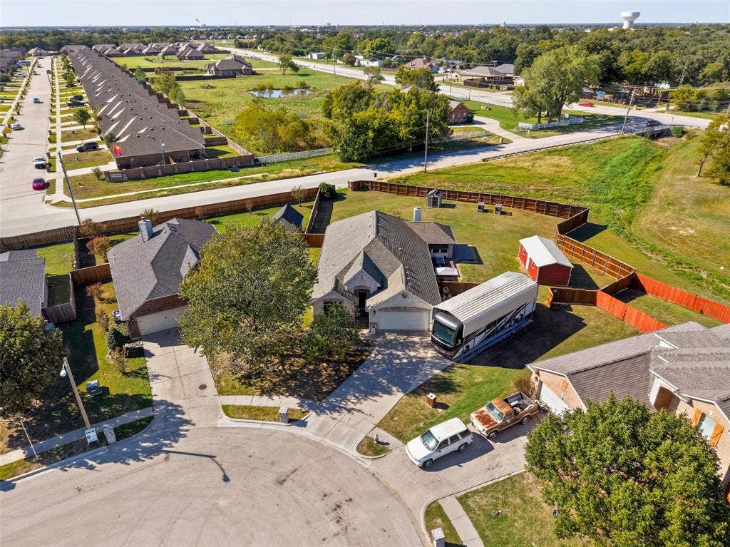 8700 Broken Bow Drive, Greenville, TX 75402 Aerial perspective of a property showing it backs up to no neighbors, and access to the double gates. BRING ALLLLL YOUR TOYS! NO NEED TO PAY A STORAGE FEE ANYMORE!