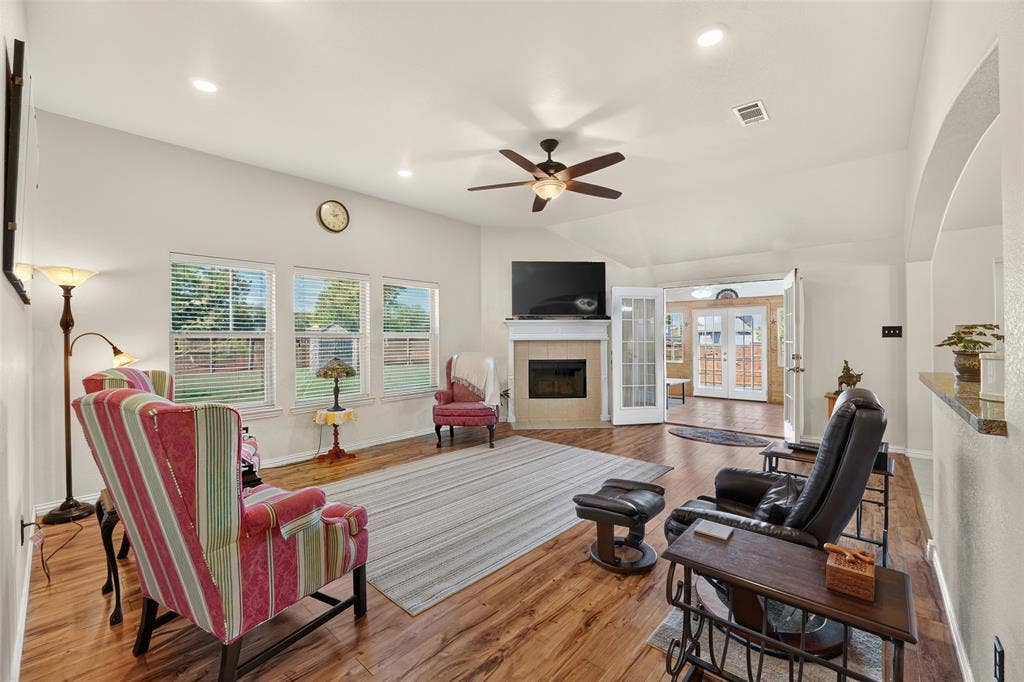 8700 Broken Bow Drive, Greenville, TX 75402 Spacious living room with vaulted ceilings, abundant natural light, a cozy fireplace, and access to the sunroom via double doors.