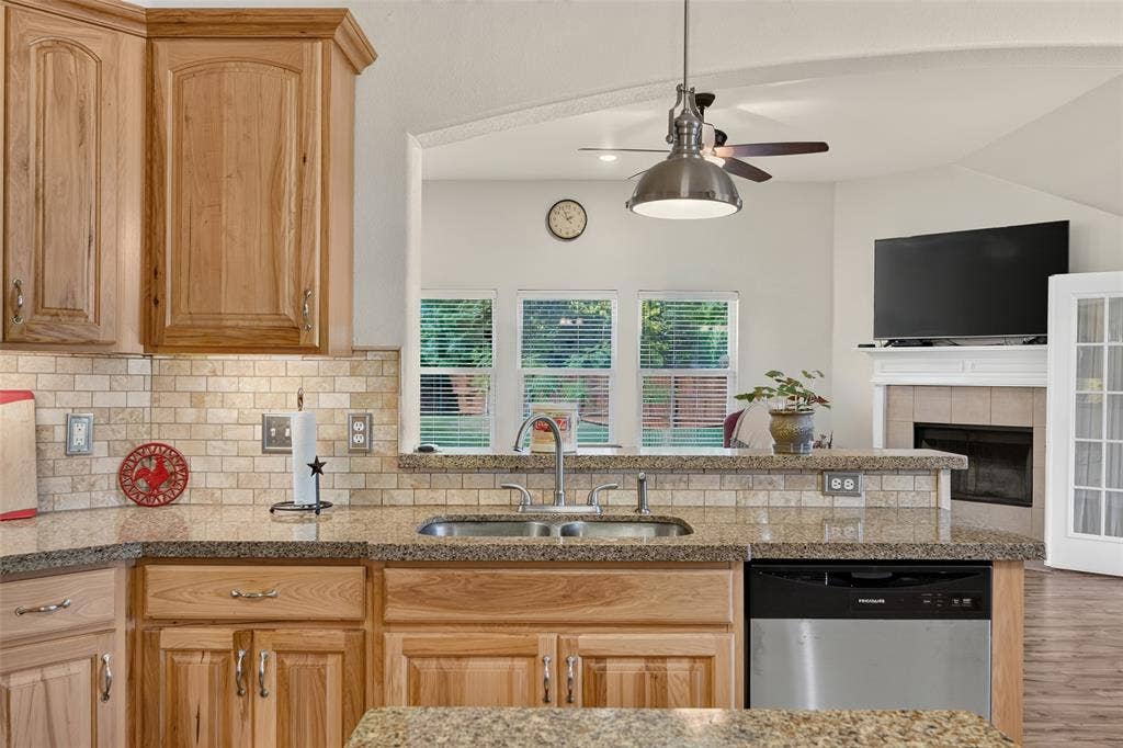 8700 Broken Bow Drive, Greenville, TX 75402 Kitchen sink with ss high-arc faucet looking into the living room and to the back yard. Binge watch your fave show while washing dishes!