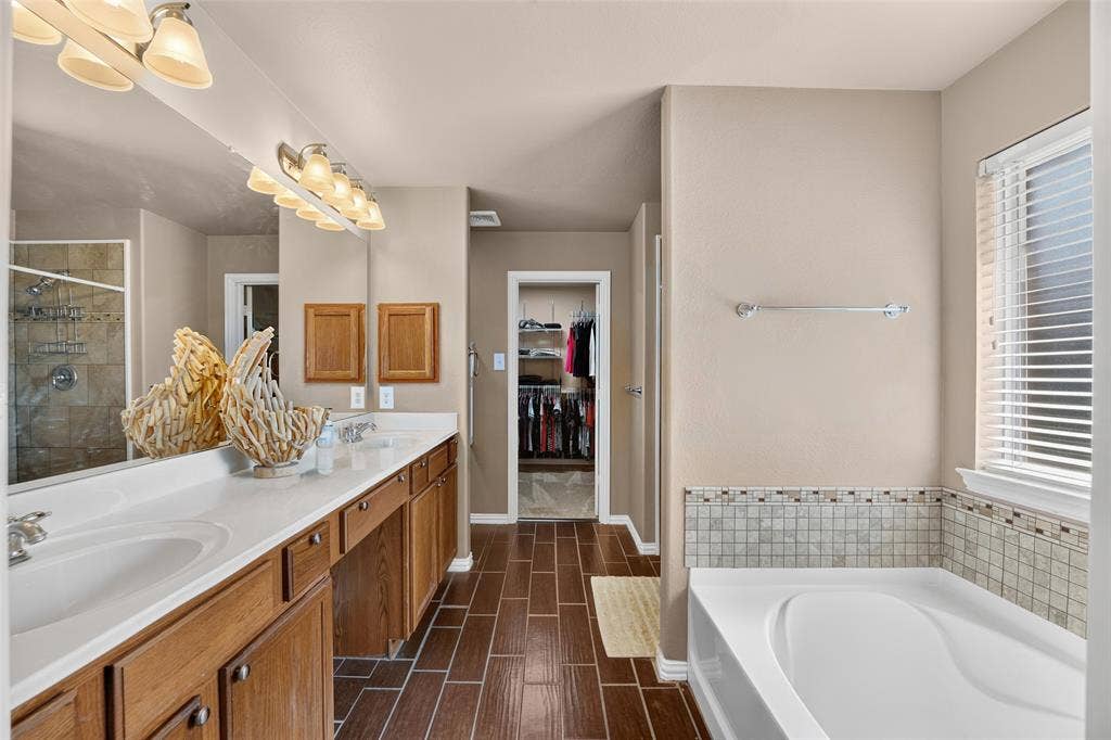 8700 Broken Bow Drive, Greenville, TX 75402 Well-appointed primary bath featuring dual vanities, a relaxing soaking tub, separate walk-in shower, and direct access to the spacious walk-in closet.