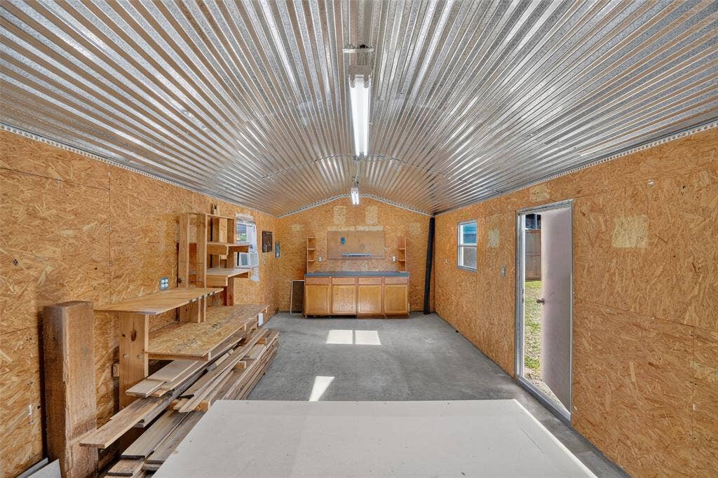 8700 Broken Bow Drive, Greenville, TX 75402 Inside of the workshop with cabinetry, lighting and a wall AC unit.