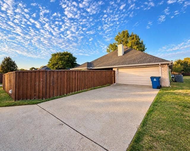 8813 Pheasant Run Drive, Rowlett, TX 75089 Driveway view gargage and fence with gate exterior security lights