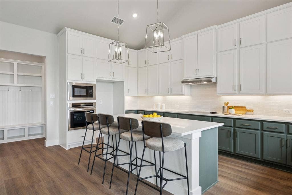 151 Quiet Waters Way, Waxahachie, TX 75165 Kitchen featuring floor-to-ceiling white cabinetry, dual-tone island base, quartz countertops, built-in wall oven and microwave, and geometric pendant lighting