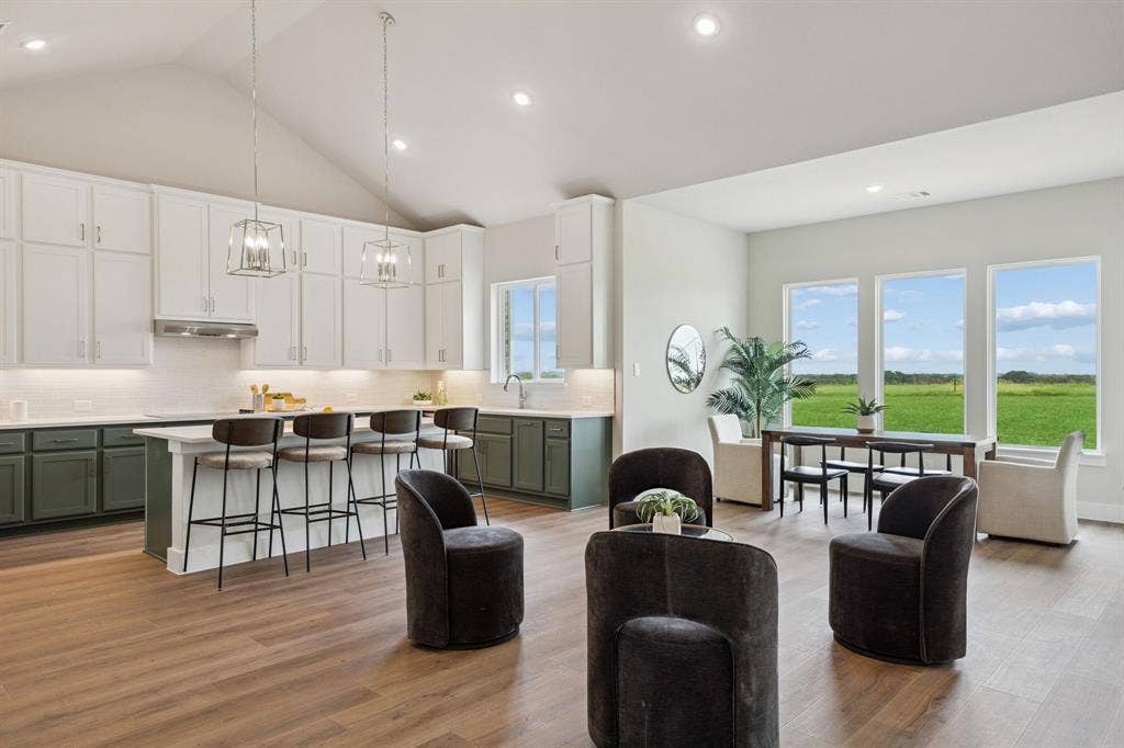 151 Quiet Waters Way, Waxahachie, TX 75165 Kitchen featuring vaulted ceilings, two-tone cabinetry, a central island with counter seating, wood-finish flooring, and expansive windows