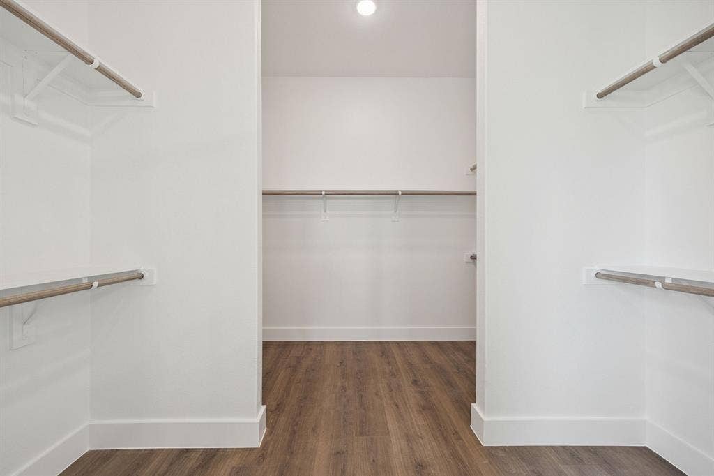 151 Quiet Waters Way, Waxahachie, TX 75165 Walk-in closet featuring wood-finish flooring, white walls, and multiple tiers of built-in shelving with integrated rods
