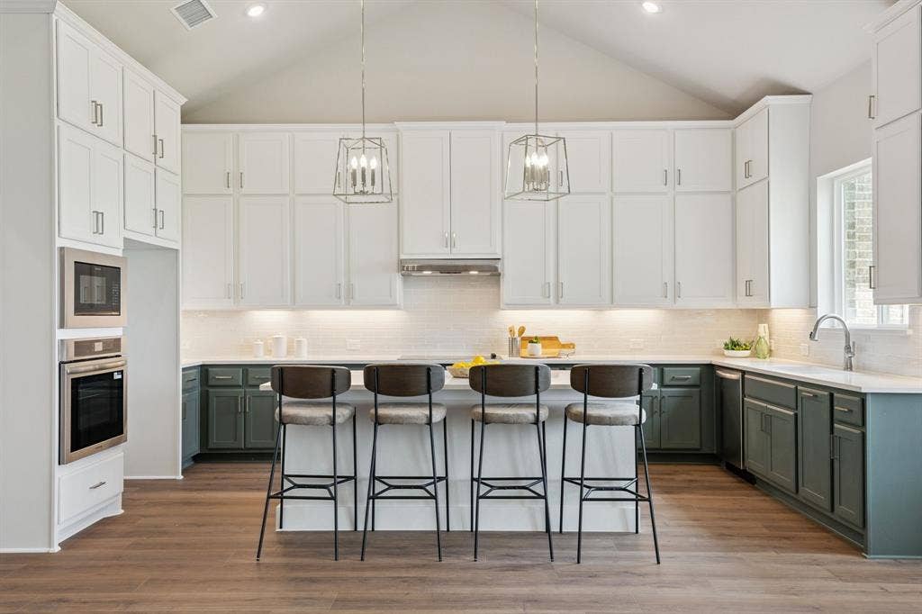 151 Quiet Waters Way, Waxahachie, TX 75165 Kitchen featuring vaulted ceilings, two-tone cabinetry, a central island, integrated stainless steel double wall ovens, and wood-finish flooring