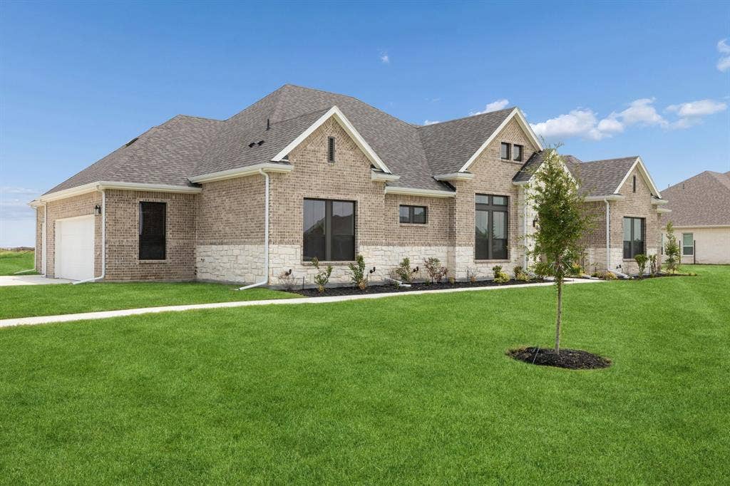 151 Quiet Waters Way, Waxahachie, TX 75165 Traditional residence featuring brick and stone masonry, multi-gabled roofline, dark-trimmed windows, and an attached multi-car garage