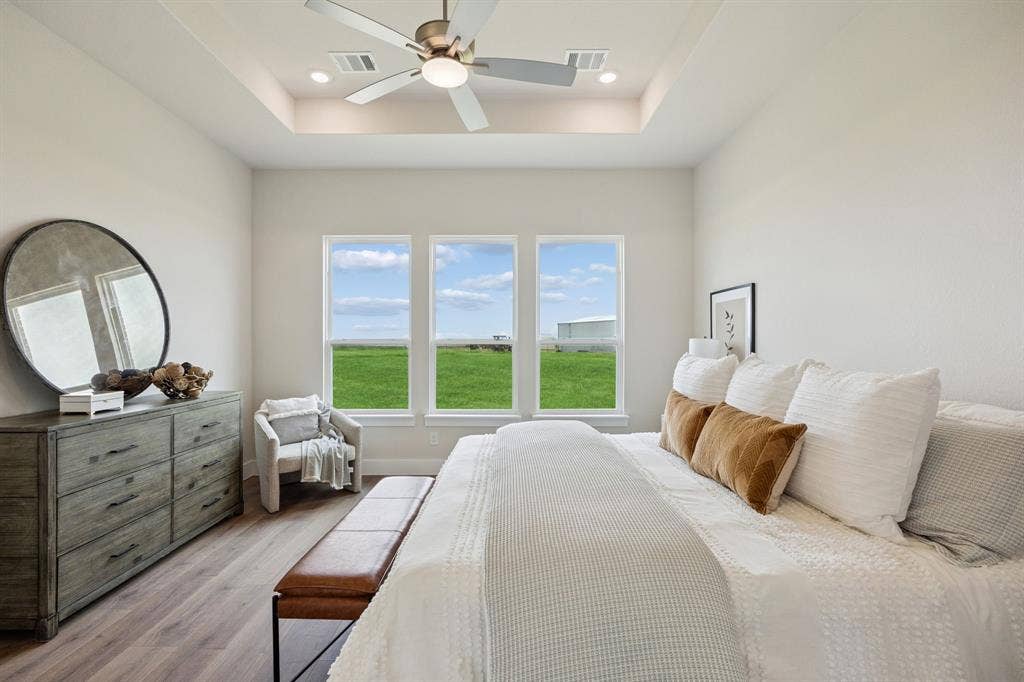 151 Quiet Waters Way, Waxahachie, TX 75165 Room with a tray ceiling, wood-finish flooring, central ceiling fan, and triple windows
