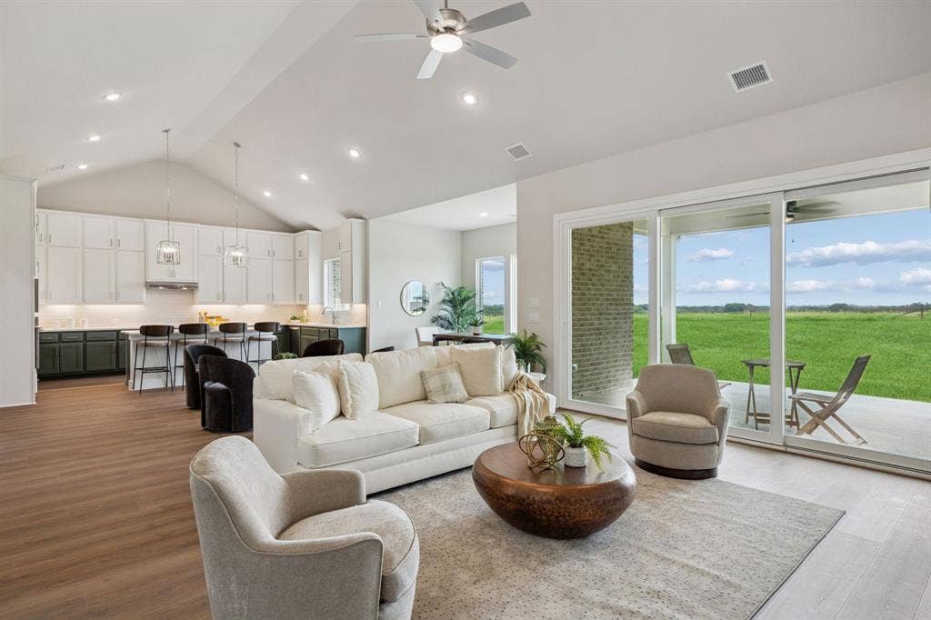 151 Quiet Waters Way, Waxahachie, TX 75165 Vaulted ceilings, open-concept kitchen with white cabinetry, wood-finish flooring, recessed lighting, and expansive glass sliding doors