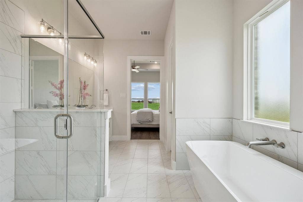 151 Quiet Waters Way, Waxahachie, TX 75165 Bathroom featuring a glass-enclosed shower with stone-finish wall tile, a deep soaking tub with a wall-mounted faucet, and tile flooring