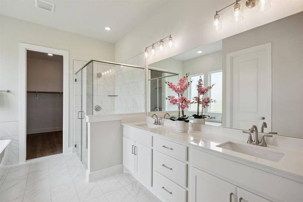 151 Quiet Waters Way, Waxahachie, TX 75165 Dual-sink vanity with quartz countertop, walk-in glass-enclosed shower featuring tiled surround, and expansive wall-mounted mirror