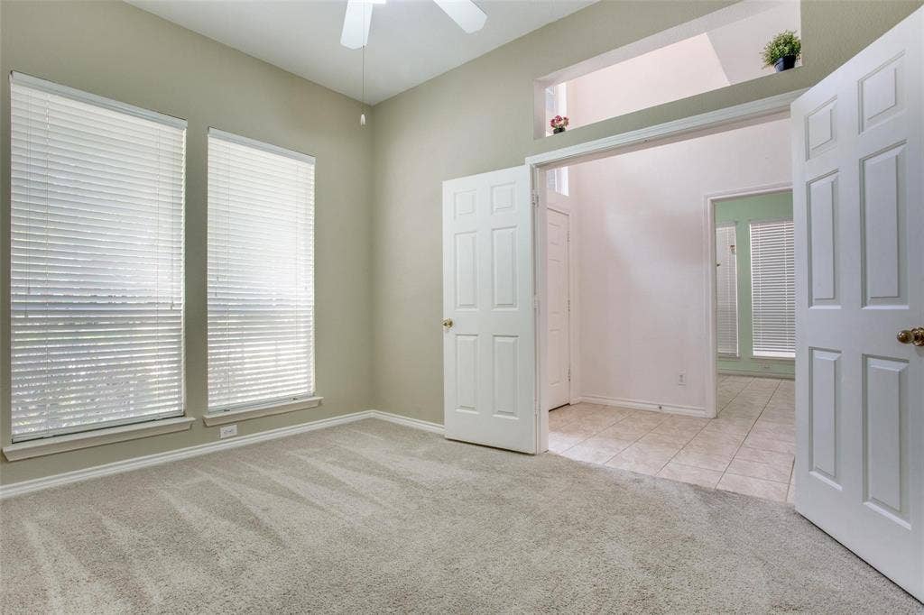 Room featuring neutral-toned carpeting, dual windows with blinds, a ceiling fan, and a recessed architectural niche