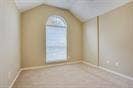 Vaulted ceiling featuring an arched window with neutral-toned wall paint and carpeted flooring