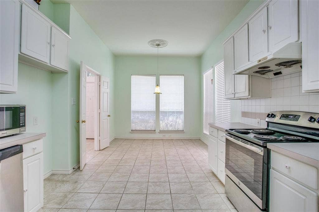 Kitchen featuring white cabinetry, tile flooring, ceramic tile backsplash, and a pendant light fixture with a decorative ceiling medallion