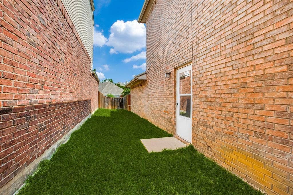 Brick exterior wall, exterior door with glass insert, concrete step, and fenced side yard