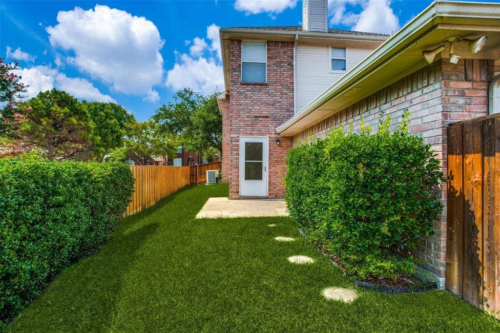 Brick and siding exterior featuring a concrete patio, wood-style privacy fencing, and mature landscaping