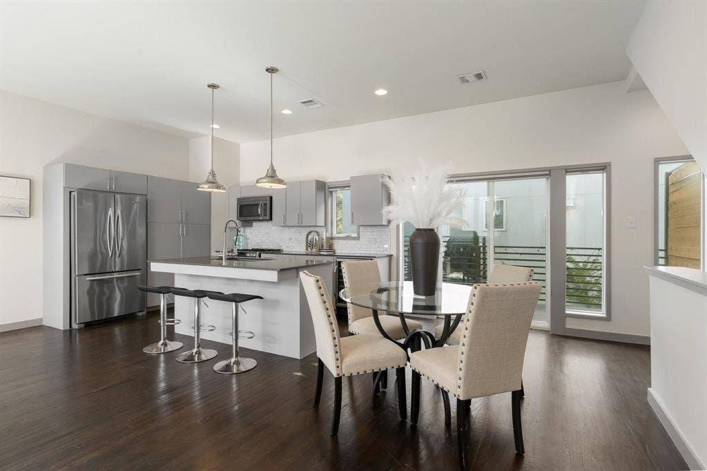 Kitchen featuring flat-panel cabinetry, a central island with a solid-surface countertop, stainless steel appliances, recessed lighting, and wood-finish flooring
