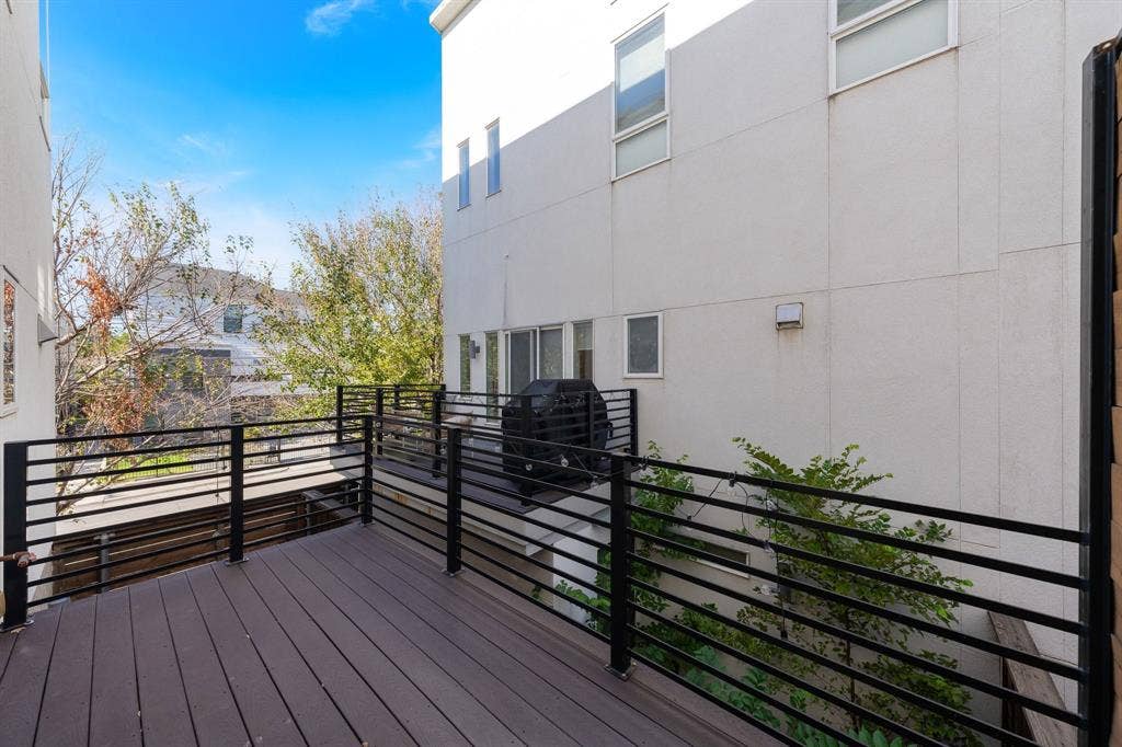 Multi-level exterior deck featuring composite decking, black metal horizontal railing, and structural stair access