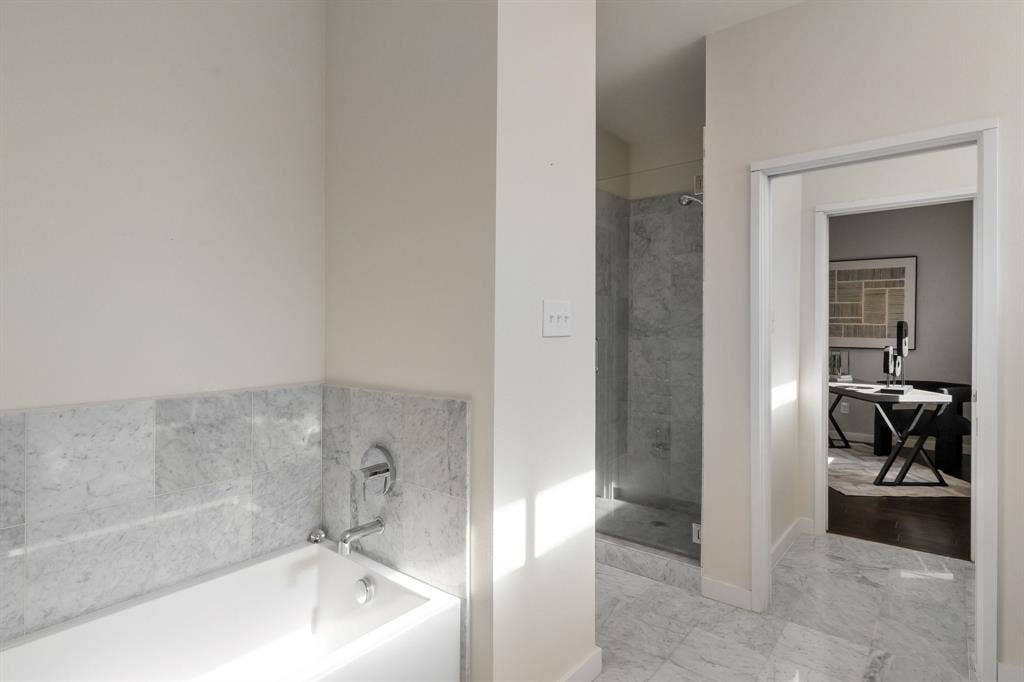 Bathroom featuring stone-tile flooring, a deep soaking tub with stone-tile surround, and a walk-in shower with a glass enclosure