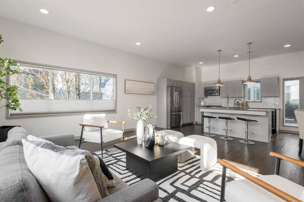 Open-concept living space featuring wood-finish flooring, recessed lighting, and a kitchen island with stone countertops