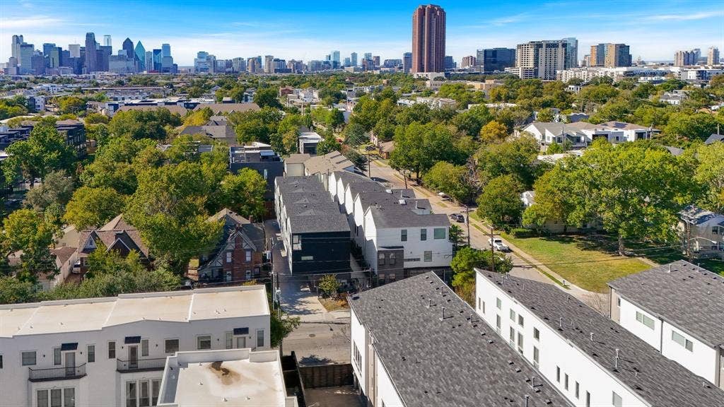Aerial perspective of a multi-story residential building featuring a dark-toned facade, pitched rooflines, and cityscape backdrop