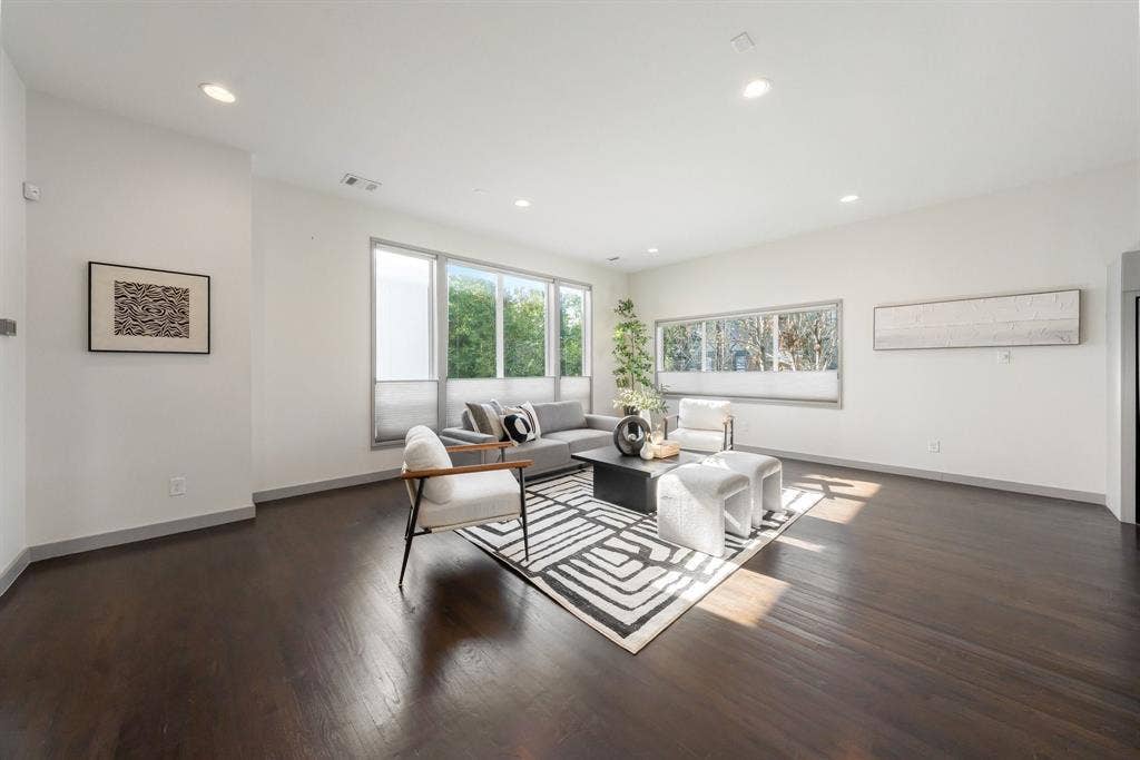 Open living area featuring dark wood-finish flooring, recessed lighting, and expansive windows