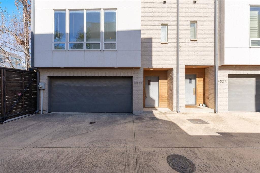 Contemporary multi-level exterior featuring light brick masonry, wood-accented recessed entryways, large multi-pane windows, and private attached garages