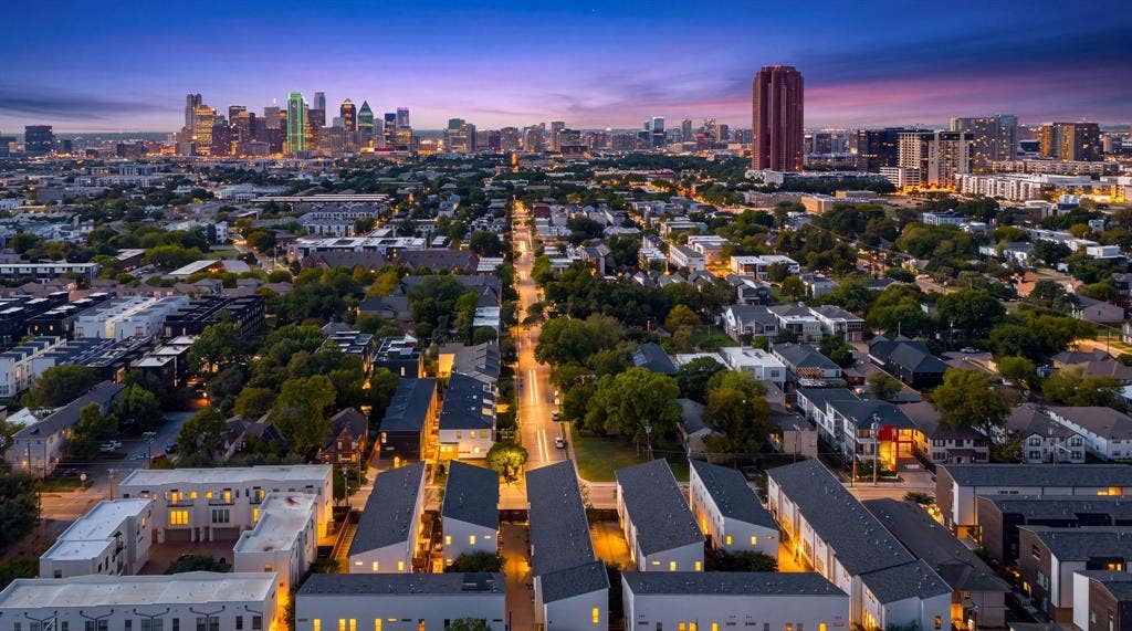 Aerial perspective featuring a prominent cityscape skyline backdrop and established neighborhood mature trees