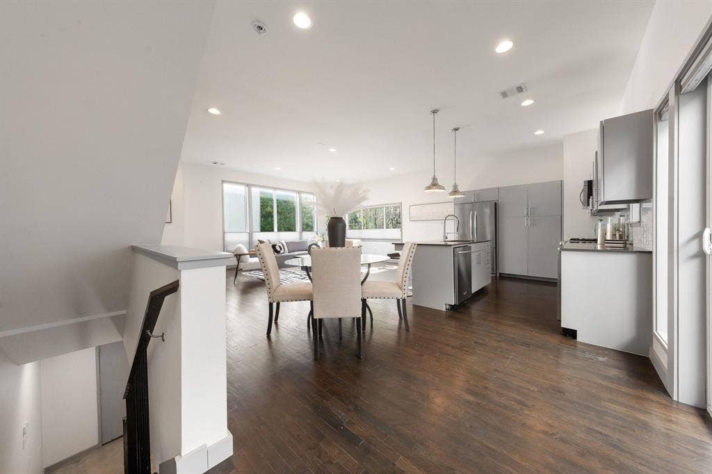 Open-concept interior featuring wood-finish flooring, recessed lighting, a center island with pendant fixtures, and neutral cabinetry